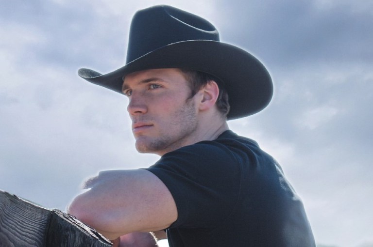 Handsome cowboy leaning on gate